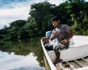 A man holds a fishing line in a boat on a river