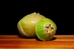 Dois frutos de cambuci sobre superfície de madeira, destacando o formato achatado característico da espécie nativa da Mata Atlântica.