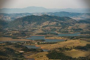 View overlooking the Mantiqueria range of Brazil's Atlantic Forest, a vast area with a winding river and mountain ranges in the distance.