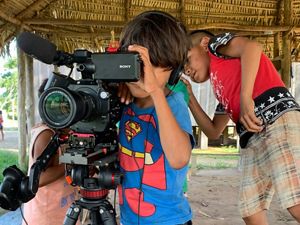 Crianças indígenas bricando com câmera de vídeo.
