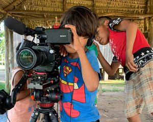 Crianças indígenas bricando com câmera de vídeo.