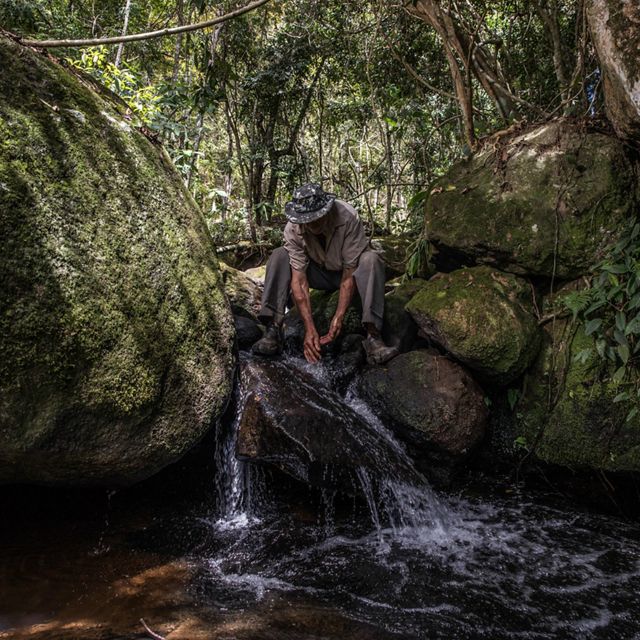 Itamar da Silva lavando as mãos em córrego que ele ajuda a preservar por meio do Pagamento por Serviços Ambientais, em sua propriedade rural em Afonso Cláudio-ES