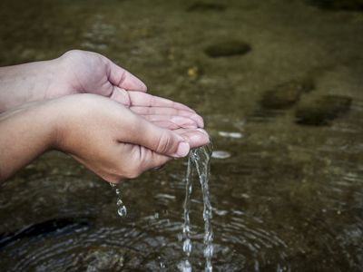 Pessoa lavando as mãos em nascente do Rio Guandu, no distrito de Lídice, em Rio Claro-RJ.
