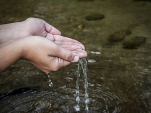 Mãos com água em rio