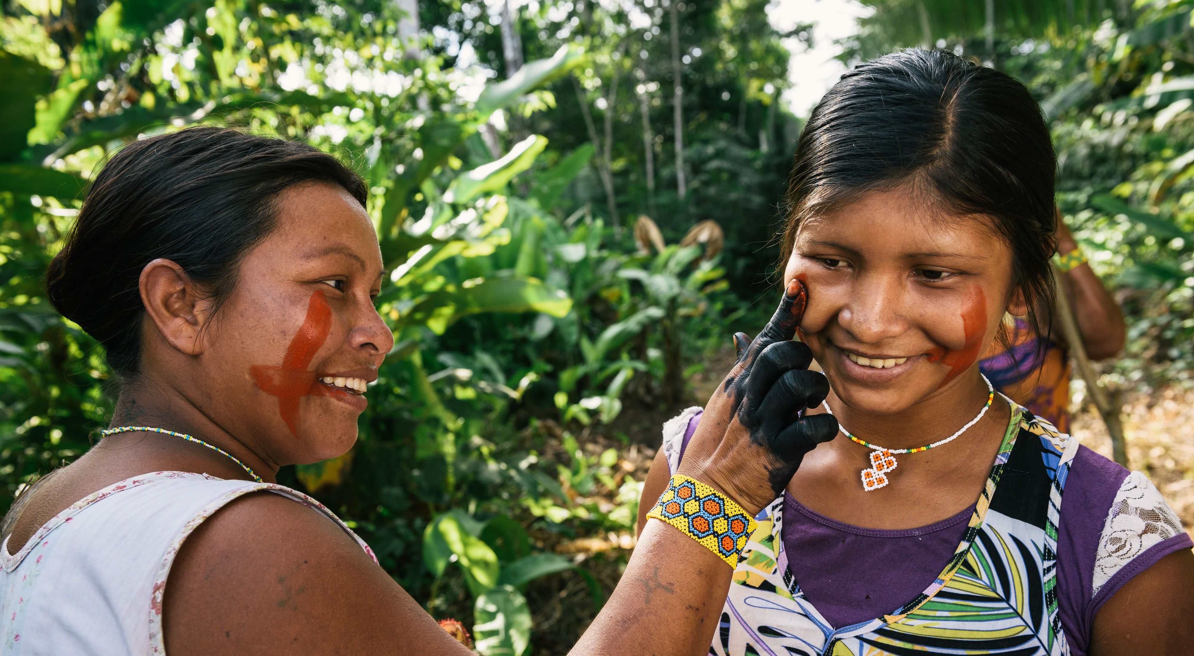 Mulheres indígenas pintando o rosto.