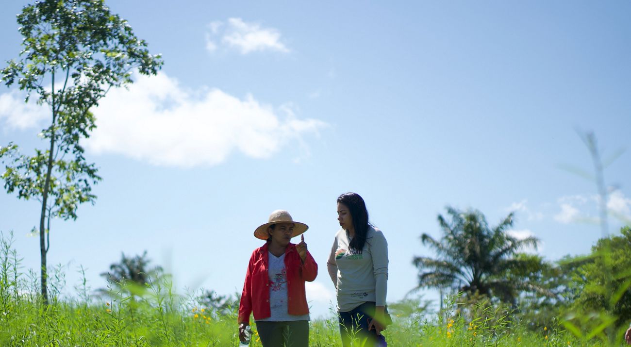 Duas mulheres conversando em área de plantio.