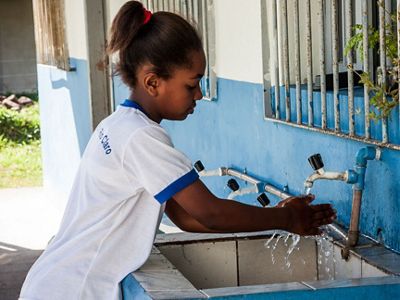 Aluna da escola municipal Rio das Pedras em Rio Claro - RJ lava suas mãos em um tanque.