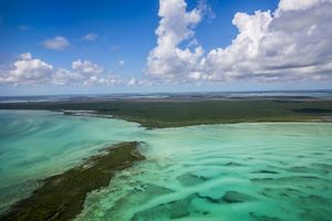 Aerial view of island and brilliant light green ocean waters along the shores.