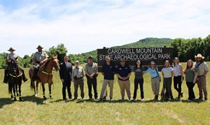 A group of people stand in front of a nature preserve sign. 