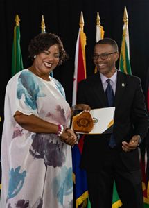 Two people stand at a podium during an award ceremony. 