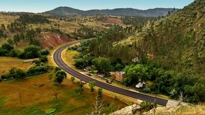 View of a canyon with a road running through it. A lone brick building sits along the roadside.