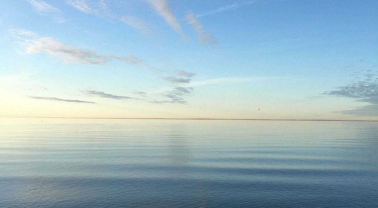 A blue sky frames calm waters along a coastline.