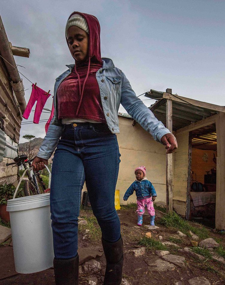 woman carries bucket of water in cape town south africa