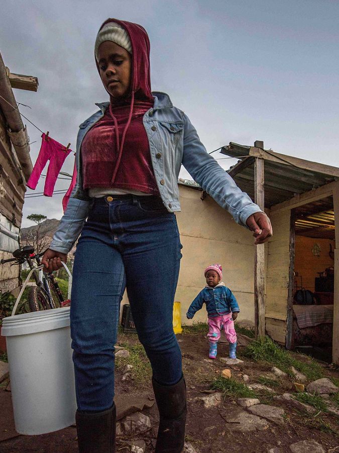 woman carries bucket of water in cape town south africa