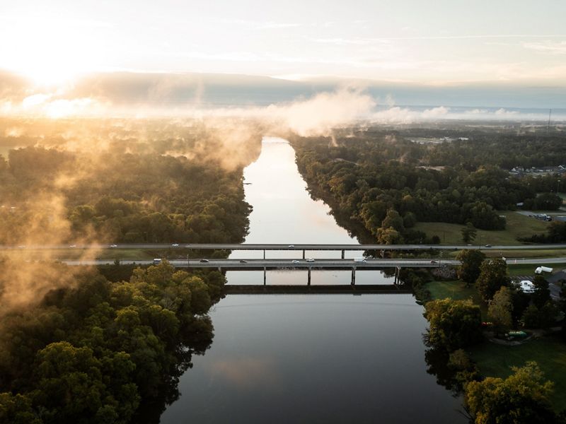 An aerial view of a river with a highway bridge crossing.