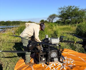 Hombre llenando el compartimento del dron con capsulas con semillas. 