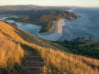 Golden light drenches the prairie grasses found along the Upper Trail at Cascade Head Preserve, Oregon, and a view of the Pa