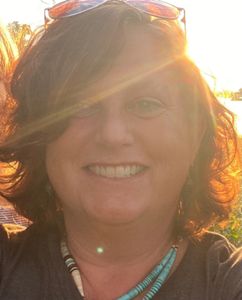 A woman with sunglasses on her head poses for a picture.