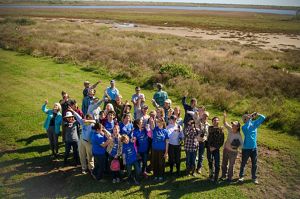 Nearly thirty bird enthusiasts gather together and pose for a group photo at the Mad Island Marsh Preserve, following a birdwatching tour.