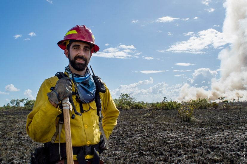 Chase McLean stands in front of an open field that has been burned over during a fire training seminar.