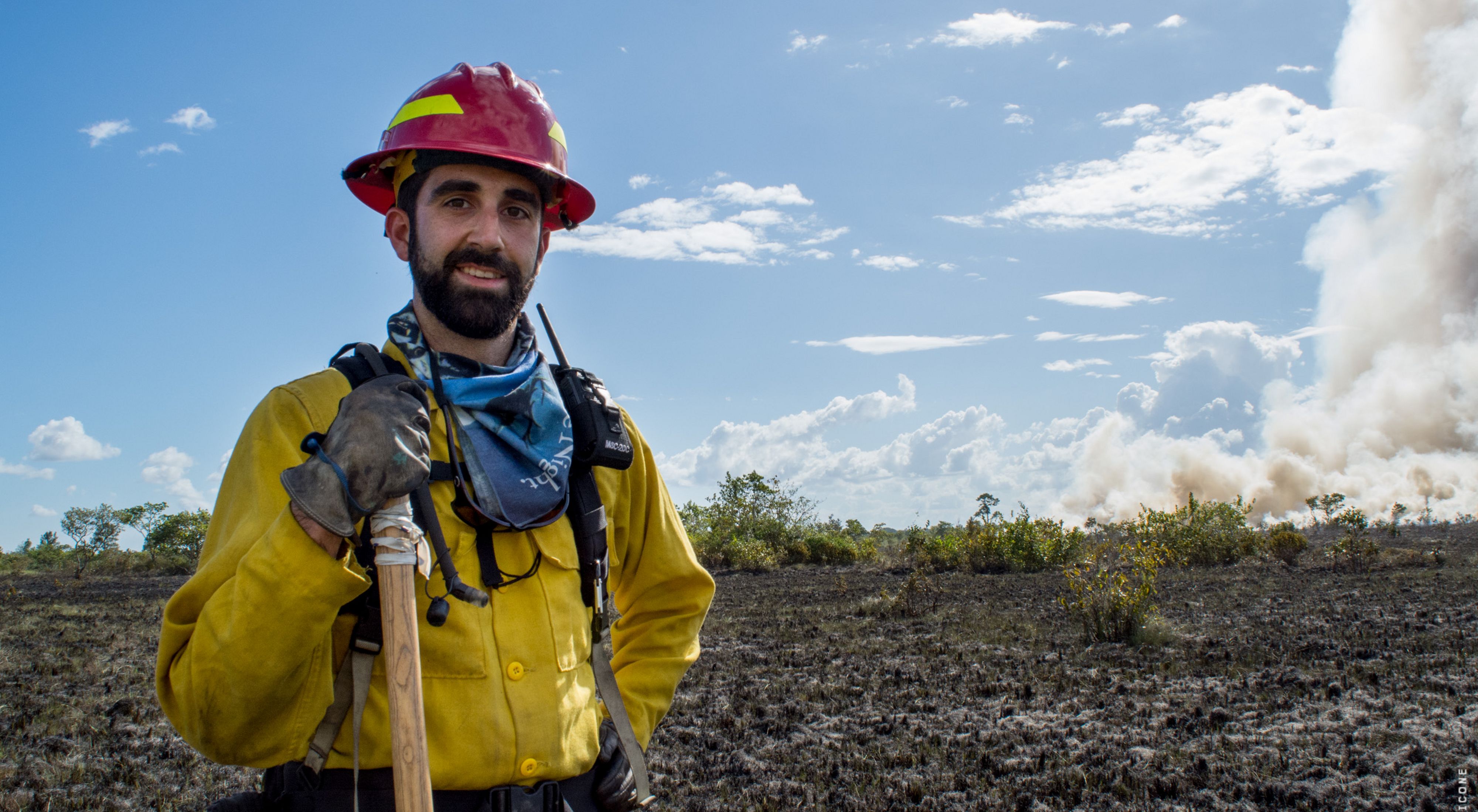 Portrait of Chase McLean standing at the edge of a controlled burn in Belize.