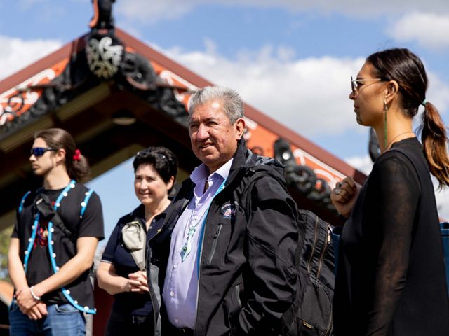 A man stands outdoors with a few other people standing near him.