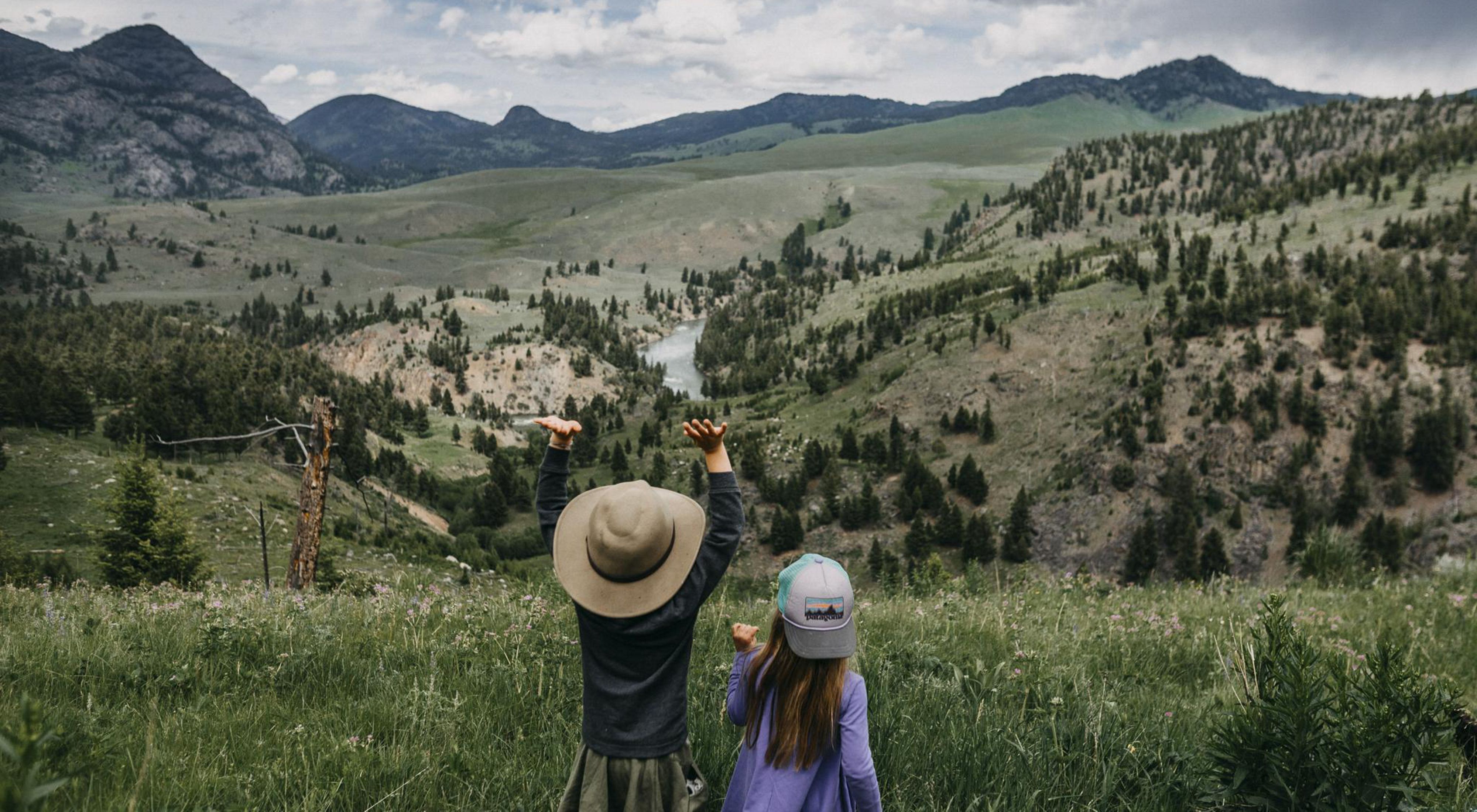 Photo of two children in foreground, sweeping views of Yellowstone National Park in background.