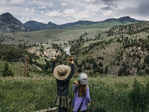 Photo of two children in foreground, sweeping views of Yellowstone National Park in background.
