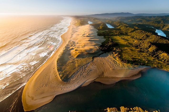 aerial image of a sandy beach and green inlands.