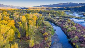 Aerial view of a river flowing with mountains in the background.
