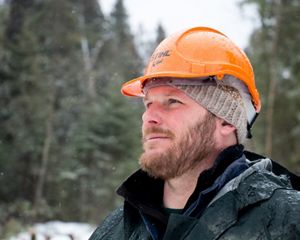 Close up of Chris Stone in the woods wearing his hard hat.