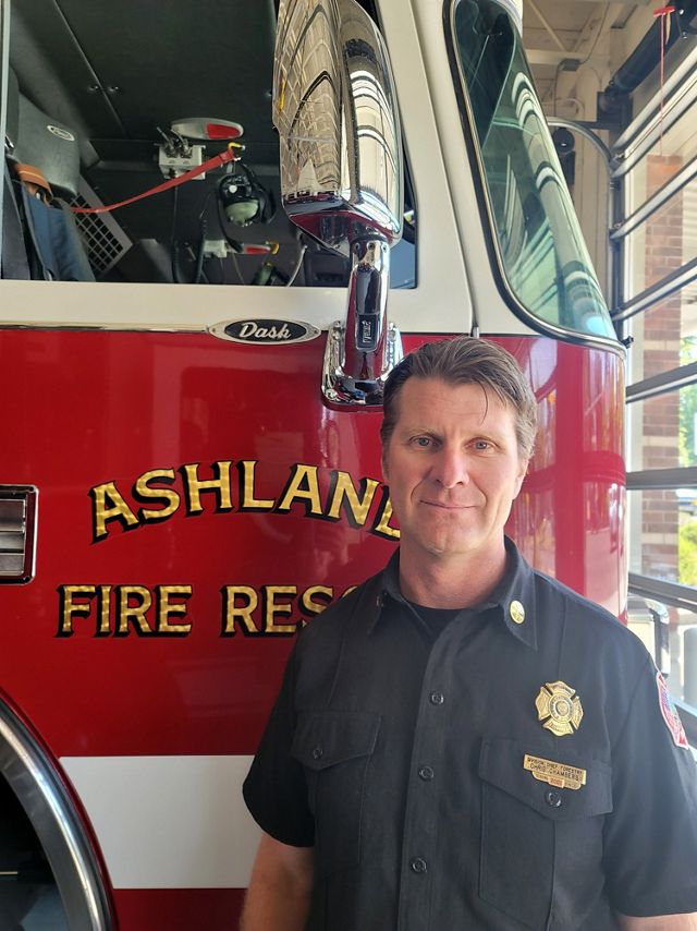 Photo of Chris Chambers standing in front of an Ashland, Oregon, fire truck.