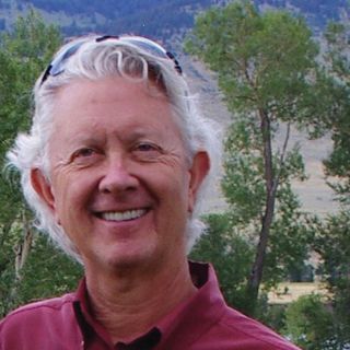 A man with sunglasses on his head smiles.