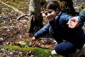 A child points to salamander eggs in a vernal pool.