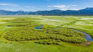 Aerial view of TNC's Flat Ranch Preserve with winding stream and mountains.