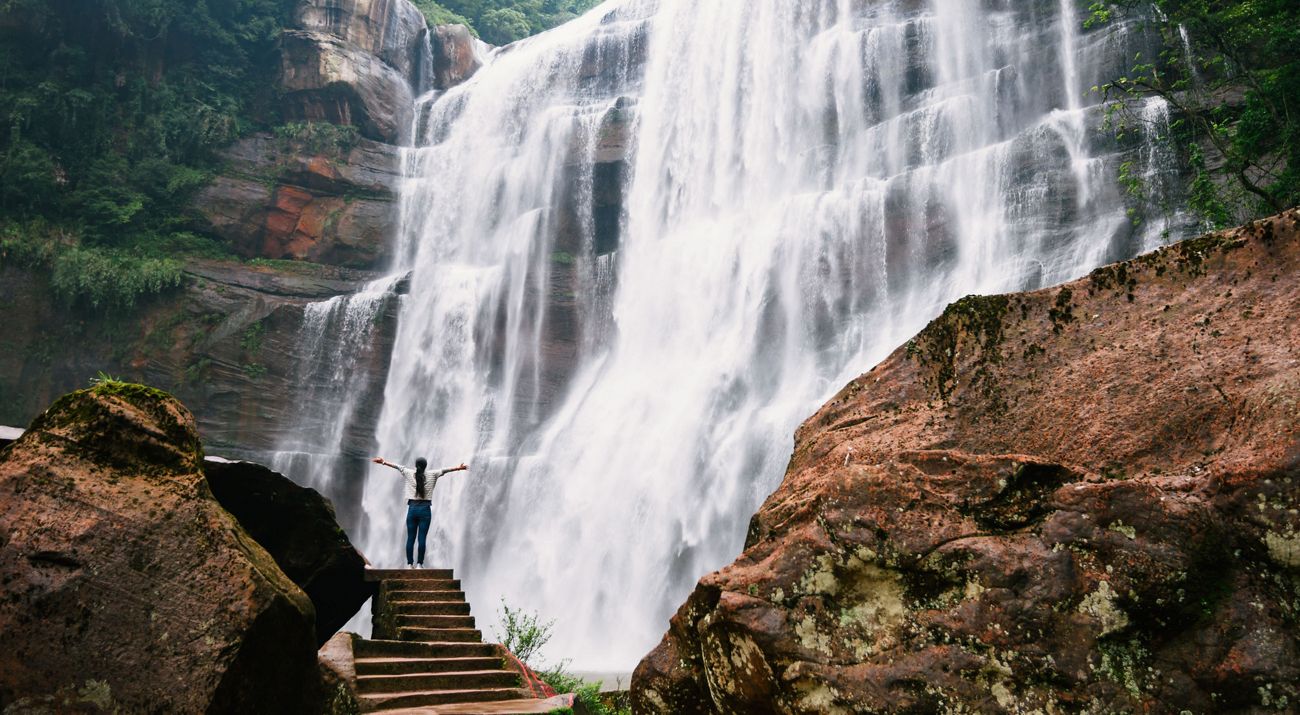 Woman standing under a waterfall.