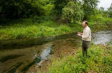 Rich Biske fishing from the grassy banks alongside a small river.