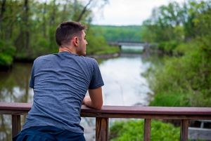 A person leaning on a railing and looking out over a river.