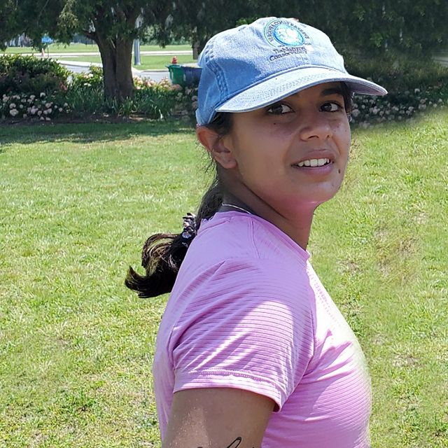 Claudia Moncada headshot. VVCR intern Claudia Moncada stands in an open park in Chincoteague during a community engagement event.