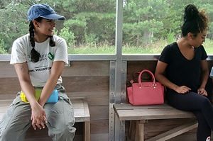 TNC intern Claudia Moncada is seated next to a mother and her young daughter in a screened in wagon during a tour of Brownsville Preserve.