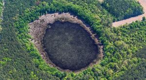 Aerial view looking down on a large pond surrounded by trees.