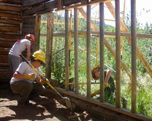 A group of people building a shed out of wood beams.