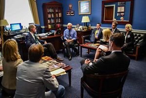A group of people sitting in a circle in a politician's office, asking questions.