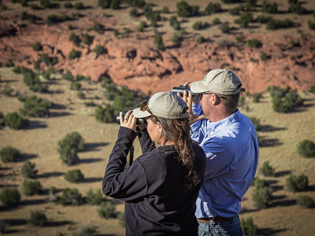 Two TNC staff look through binoculars over a vast landscape of canyonlands of JE Canyon Ranch.