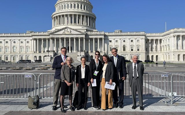 A group of people in suits standing in front of the U.S. Capitol building.