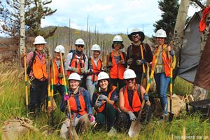 Two women standing in a field against trees.
