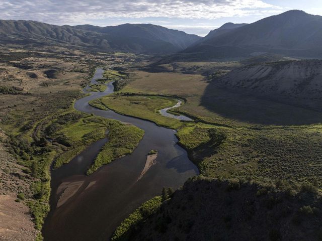 An aerial image of a wide river flowing through a valley.