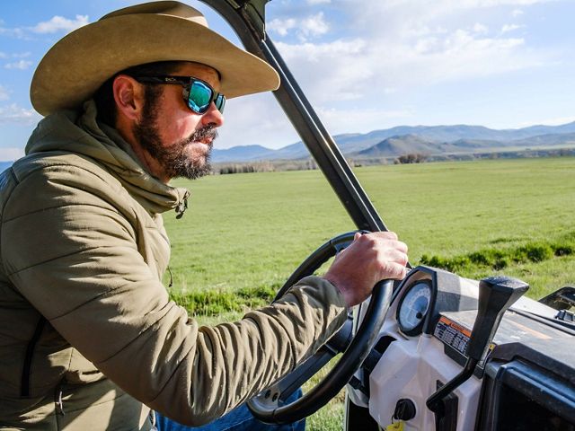 Paul Bruchez driving a tractor through a grass farm.