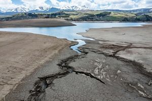 Cracks in mud lead up to a shallow pond.
