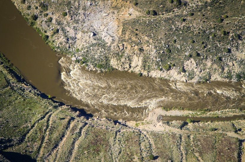 An aerial shot of the Maybell ditch with muddy water flowing between arid banks.
